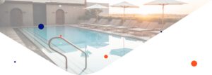 imagen de una piscina al atardecer rodeada de tumbonas y sombrillas